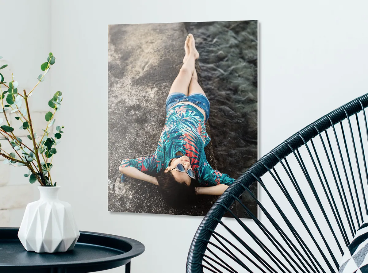Forex Wandbild 30x40 mit einem Motiv einer Frau, die in sommerlicher Kleidung an einem Schwarzen Strand liegt.